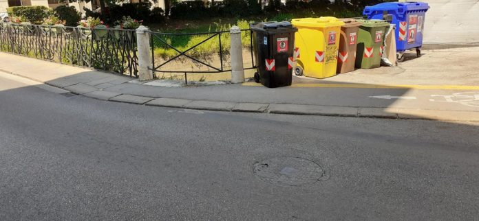 ciclabile che sfocia in marciapiede e bidone spazzatura